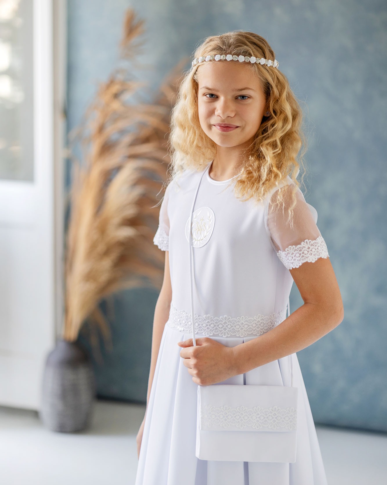 Dziewczynka w sukienko-albie komunijnej ze zdobieniami w pasie i przy rękawach
